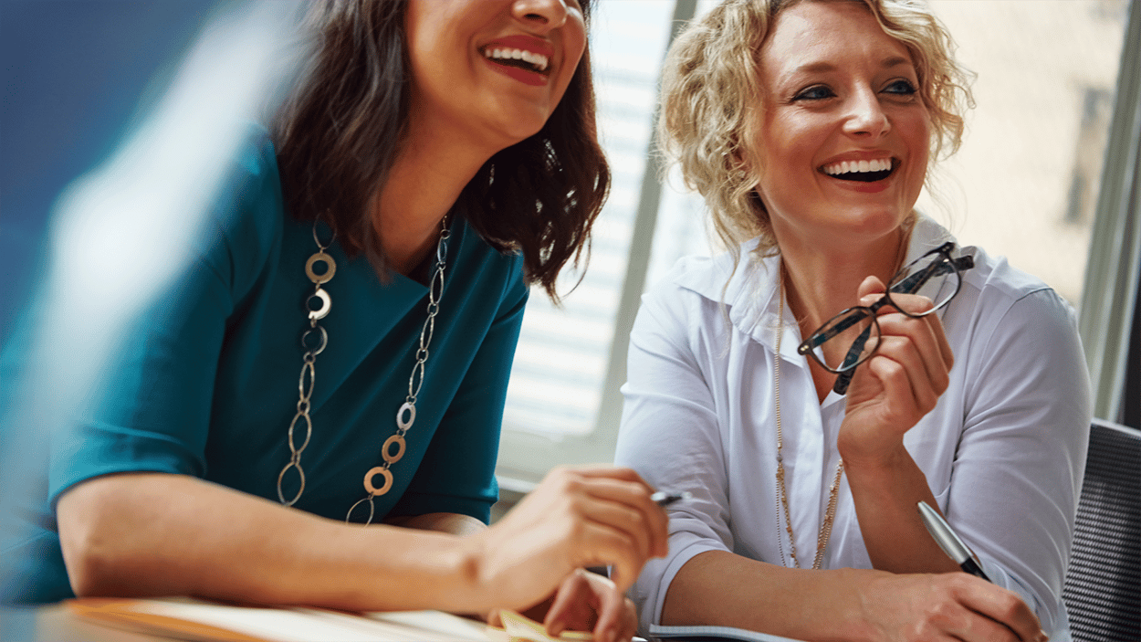 Women in meeting, smiling - Behavioural metrics can even reveal what motivates employees and makes them unique.