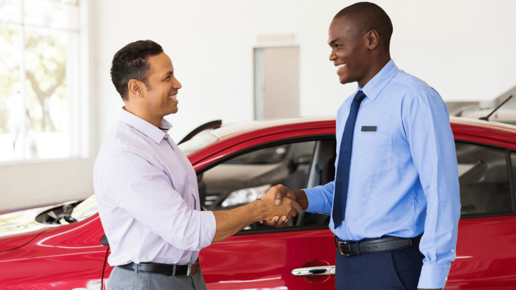 Salesman and customer shake hands on sale of car