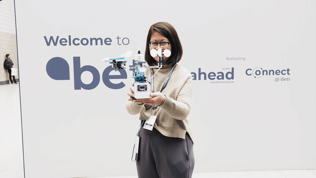 BETT 2023 - woman holds small robot in front of bett banner