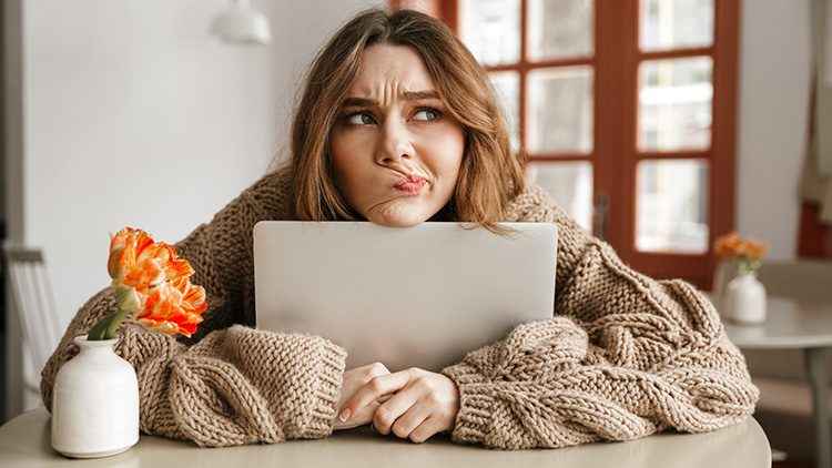 Bad UX can leaver users confused. A woman in a sweater hugs her laptop with a confused expression.