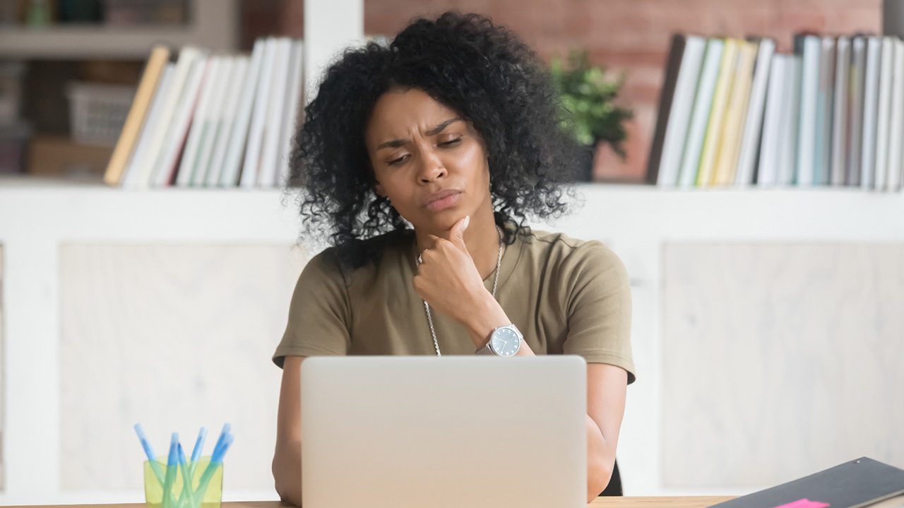 Woman in front of laptop with a questioning expression on her face.