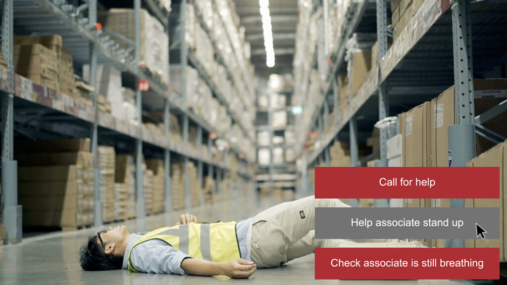 A warehouse with boxes on shelves. A worker in a high-vis vest has fallen. Choices appear on screen.