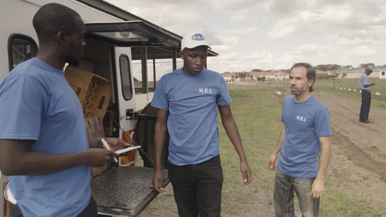 Field Security Management Course still: Shows a mixed team of local and international NGO staff having a discussion while loading a vehicle.